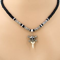 a skull and crossbone necklace on a mannequin's neck with black beads