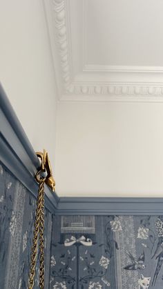 a blue and white wall with a gold chain hanging from it's center corner