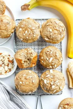 several muffins on a cooling rack with bananas and other food items around them