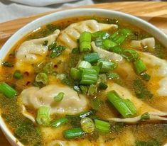 a white bowl filled with dumplings and green onions