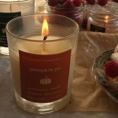 a lit candle sitting on top of a table next to muffins and raspberries