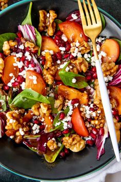 a salad with spinach, carrots, and nuts on a plate next to a fork