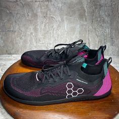 a pair of black and pink shoes sitting on top of a wooden table