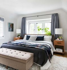 a bedroom with a large bed and white carpeted flooring in front of two windows