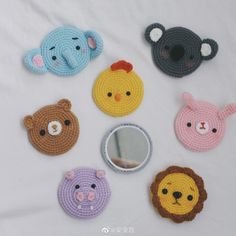 crocheted animal coasters are arranged on a white surface with a mirror in the middle