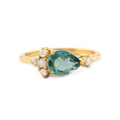 a gold ring with an oval green stone and three small white diamonds on the side