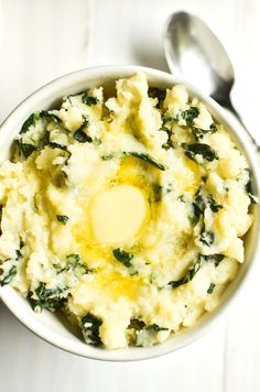 a white bowl filled with mashed potatoes topped with an egg and spinach sauce