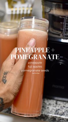 a person holding up a drink in front of an appliance with the words pineapple and pomegranate on it