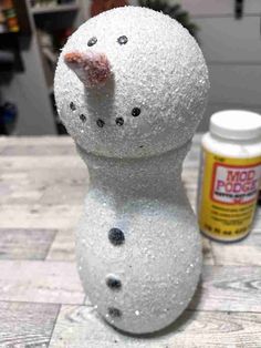 a snowman made out of foam sitting on top of a wooden table next to some glue