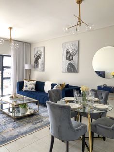 a living room filled with furniture and a glass table surrounded by blue velvet couches