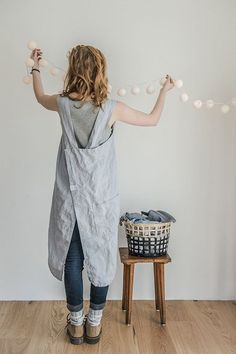 a woman standing in front of a white wall with lights hanging from it's sides