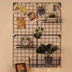 there is a wire rack with plants and pictures on it, along with a clock