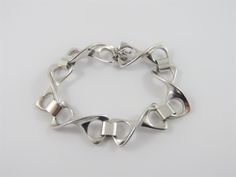 "This is a sterling silver  7 1/2 inch  Twisted Figure 8 linked bracelet.  The bracelet has 6 figure 8 links with broad oval links connecting them together.  The clasp has a figure 8 safety catch. The bracelet has a high polished finish and is in very good condition. The bracelet measures 7 1/2\" long x 5/8\" wide The total weight is 35.55 grams. Marked:  Sterling Inventory #2842" Modern Silver Bracelet With Hook And Links, Modern Sterling Silver Bracelet With Polished Oval Link, Modern Silver Link Bracelet, Modern Sterling Silver Bracelet With Oval Link Oyster, Modern Silver Chain Bracelet With Clasp, Formal Sterling Silver Bracelet With Hook And Links, Formal Sterling Silver Link Bracelet With Polished Finish, Sterling Silver Formal Bracelet With Hook And Links, Silver Bracelets With Hook And Links For Formal Occasions