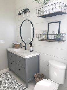 a white toilet sitting next to a sink in a bathroom under a mirror and shelves