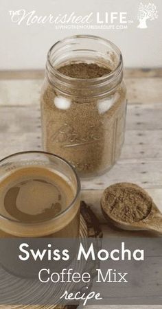 a cup of coffee sitting on top of a wooden table next to a spoon and jar