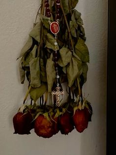 a clock hanging on the side of a wall next to red flowers and green leaves