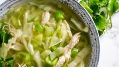 a bowl filled with soup and vegetables on top of a table