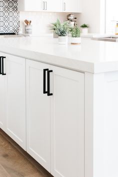 a kitchen with white cabinets and black handles