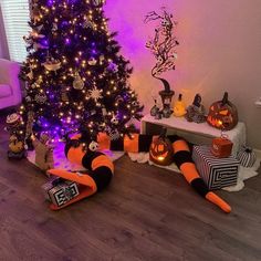 a decorated christmas tree in the corner of a living room with purple lights and decorations