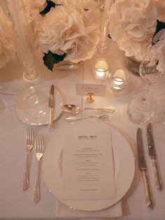 the table is set with white flowers and silverware