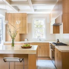 a kitchen with wooden cabinets and an island in front of a window that has a bowl of fruit on it