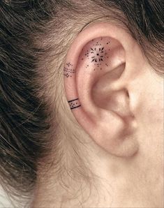 a woman's ear with an arrow and stars tattoo on the side of her ear