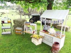 an outdoor market with hay bales, lemons and drinks on the grass under a tree