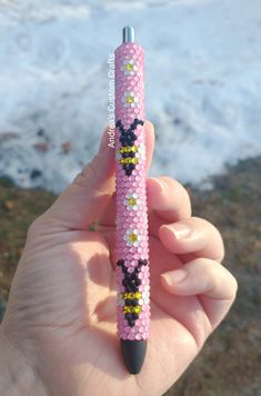 a person is holding a pink pen with beads on it