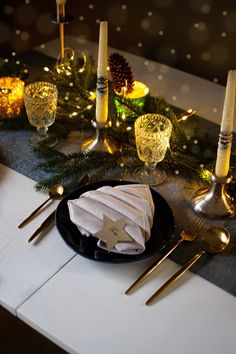 a black plate topped with napkins and silverware next to candles on a table