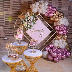 three tables with cakes and desserts on them in front of a balloon arch decorated with flowers