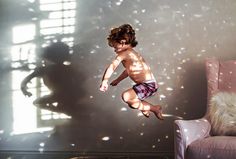 a young boy jumping into the air in front of a wall with bubbles on it