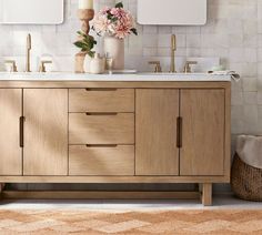 a bathroom with two sinks and mirrors on the wall next to a basket full of flowers