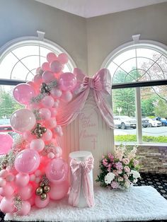 a pink and white balloon arch with balloons