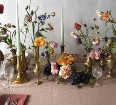 a table topped with lots of vases filled with flowers and candles next to each other