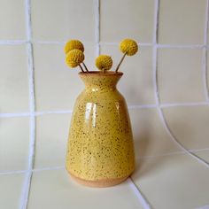 a yellow vase sitting on top of a white tiled wall