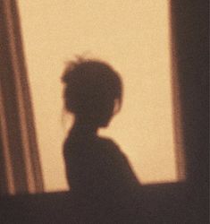 the shadow of a child's head is shown in front of a window with curtains