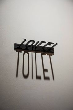 the word toilet spelled with black letters on a white wall