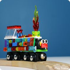 a toy train with lots of colorful blocks on the front and sides, sitting on top of a piece of wood