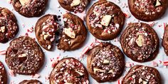 chocolate cookies with candy canes and sprinkles are arranged on a white surface