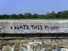 graffiti on the side of a stone wall that says i hate this town