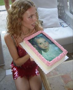 a woman holding up a cake with a photo on it in front of her face