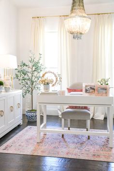 a living room with white furniture and a chandelier hanging from the ceiling above it