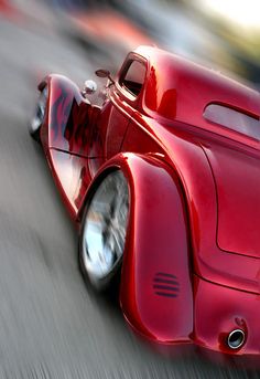 a red car driving down a street next to tall buildings