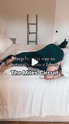 a woman laying on top of a bed next to a cat