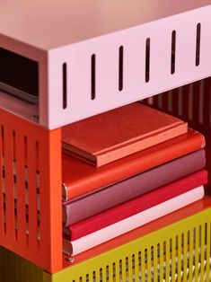 a stack of books sitting on top of a yellow shelf next to a red box