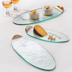 three plates with desserts on them sitting next to wine glasses and utensils