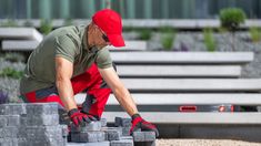 a man in red gloves and safety glasses working on cement blocks