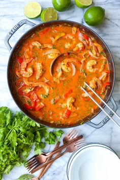 a pan filled with shrimp and vegetables next to some limes