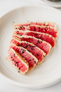 slices of sliced up meat on a white plate with black pepper sprinkles