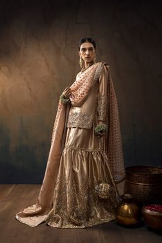 A Tissue short shirt in Buff with full sleeves, paired with a matching Two-legged gharara. The set includes an Apricot Organza dupatta with work on all four sides and an additional Shawl in Shimmer silk. Discover our Indian wedding collection, featuring bespoke outfits, gowns, and ghararas that embody the essence of tradition and modernity for your special day.In the spotlight is a captivating ensemble featuring a Buff Tissue short shirt with full sleeves, flawlessly paired with a matching Buff Chunni Ceremony, Jaggo Night, Pakistani Bridal Dresses Online, Qabool Hai, Bridal Gharara, Classy Couture, Gharara Designs, Desi Outfits, Desi Wedding Dresses